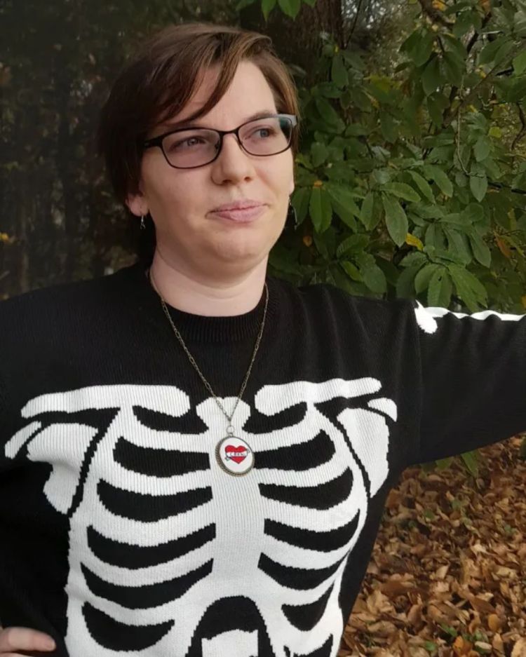 A portrait of Antonija Mežnarić, a dark-haired white woman with glasses, wearing a ribcage skeleton print sweater.